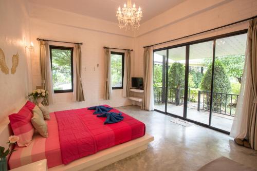 a bedroom with a red bed and a large window at The Harmony Resort in Suan Phung