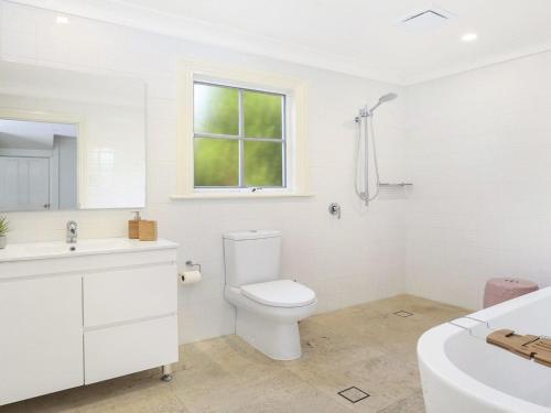 een witte badkamer met een toilet en een wastafel bij Duncraig House in Bundanoon