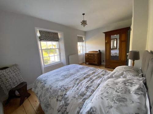 a bedroom with a bed and a dresser and windows at Pillar House in Cockermouth