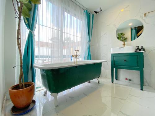 a bathroom with a large green tub and a plant at Lacasa May in Da Lat
