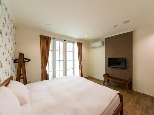 1 dormitorio con 1 cama blanca grande y TV en Kenting Lian Nan Wan, en Nanwan