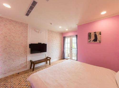 a bedroom with a pink wall with a bed and a tv at Pretty Nanwan B&B in Nanwan