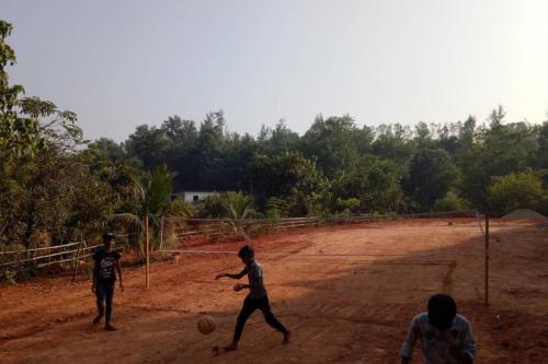 three boys playing soccer on a dirt field at NIDHIVANA FARMS & RESORT, bakrebail-salethoor rd, Mangalore in Mangalore