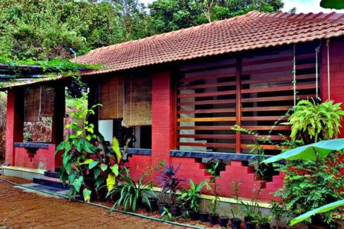 a red house in the middle of a forest at NIDHIVANA FARMS & RESORT, bakrebail-salethoor rd, Mangalore in Mangalore