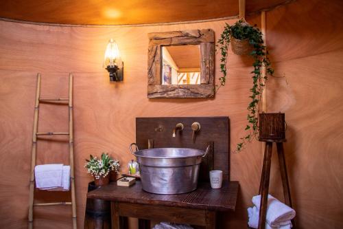 Baño con cubo sobre una mesa con espejo en 2 CUORI E 1 YURTA Glamping in Tuscany - Adults Only en Asciano
