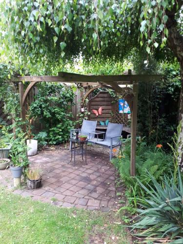 a patio with two chairs and a bench under a pergola at B&B overnachting de Margriet in Hardenberg