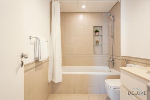 a bathroom with a tub and a toilet and a sink at Blissful 1BR in Safi Town Square by Deluxe Holiday Homes in Dubai