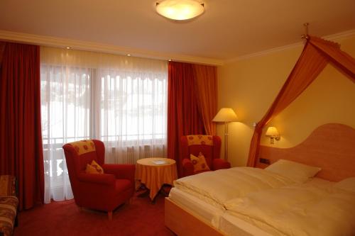 a hotel room with a bed and two chairs at Ferienhotel Ödenhof in Baiersbronn