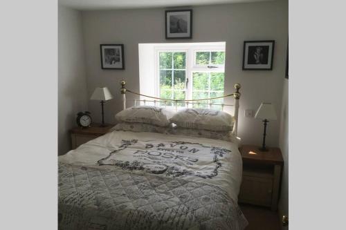sypialnia z łóżkiem z białą kołdrą i oknem w obiekcie Dartmoor National Park- Romantic Cottage w mieście Lustleigh