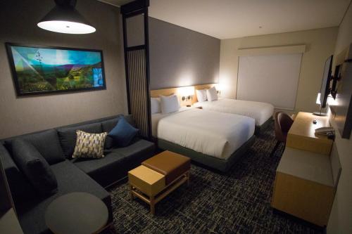 a hotel room with two beds and a couch at Hyatt Place Saltillo in Saltillo