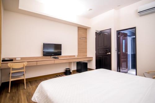 馬公市的住宿－沐夏風情民宿，一间卧室配有一张床和一张书桌及电视