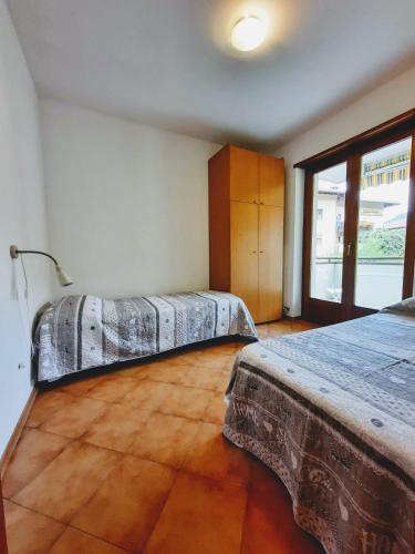 a bedroom with two beds and a large window at Comano Terme Apart in Comano Terme
