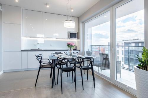 a kitchen and dining room with a table and chairs at Manufaktura SKYLINE by PinPoint in Łódź