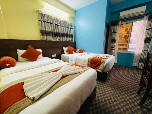 una camera d'albergo con 2 letti con cuscini arancioni di Rosemary Homes Pokhara a Pokhara