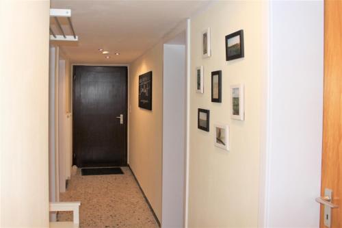 a hallway with a black door and pictures on the walls at Ferienwohnung Landlust Wolfenbüttel in Klein Denkte