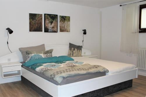 a white bedroom with a bed and two lamps at Ferienwohnung Landlust Wolfenbüttel in Klein Denkte