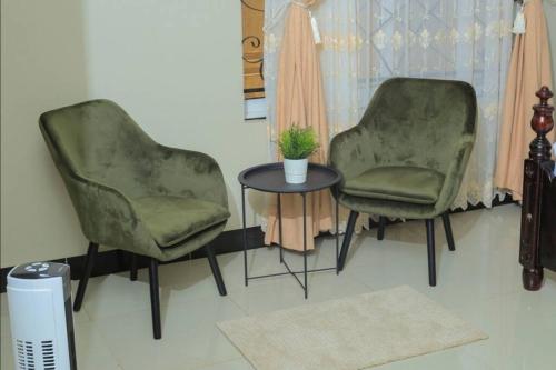 two green chairs and a table in a room at PNG Guest house Kitende in Kampala