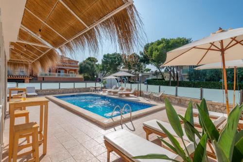 a swimming pool with chairs and an umbrella at Bauló Mar Apartments in Can Picafort