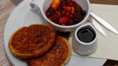 a plate of food with pancakes and a bowl of fruit at Suit' & Frühstück Zum Latschen - Adults Only in Mauth