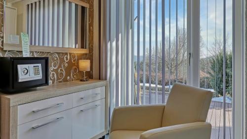 a living room with a tv and a chair and a window at Suit' & Frühstück Zum Latschen - Adults Only in Mauth
