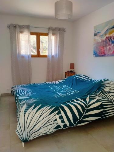 - un lit avec une couette bleue dans une chambre dans l'établissement Gîte du domaine de l'Arbre de Vie, à Saint-Chamas