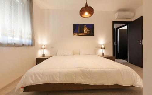 a bedroom with a large white bed and two lamps at Urban Homy Gorizia in Gorizia