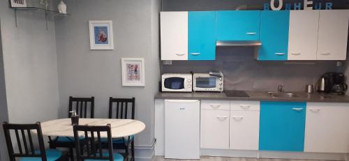 a kitchen with a table and chairs and blue cabinets at Au Coup de Cœur in Colmar
