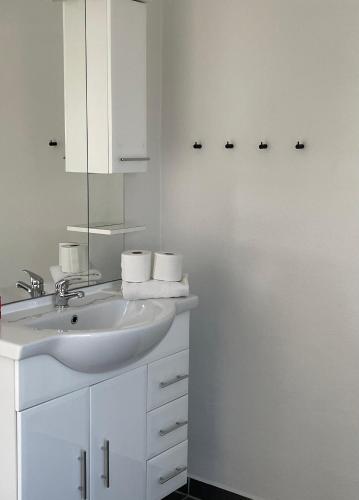 a white bathroom with a sink and a mirror at Surfers Paradise Apartments in Hvide Sande