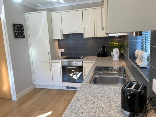 a kitchen with white cabinets and a sink at Mill Pond View in Pembroke