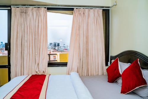 帕坦KBB Hotel and Apartments Hosted by Hostmandu的一间卧室配有一张带红色枕头的床和一扇窗户