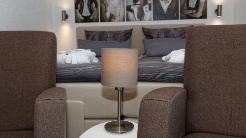 a bedroom with a bed and a lamp and two chairs at Suit' & Frühstück Zum Latschen - Adults Only in Mauth