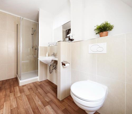 a white bathroom with a toilet and a sink at Hotel Jensen in Lübeck