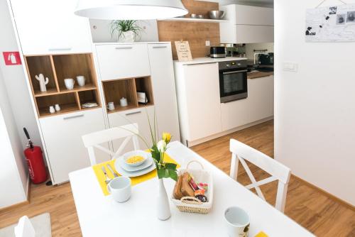 een witte keuken met een witte tafel en stoelen bij Apartment ALMA - to travel is to live in Celje
