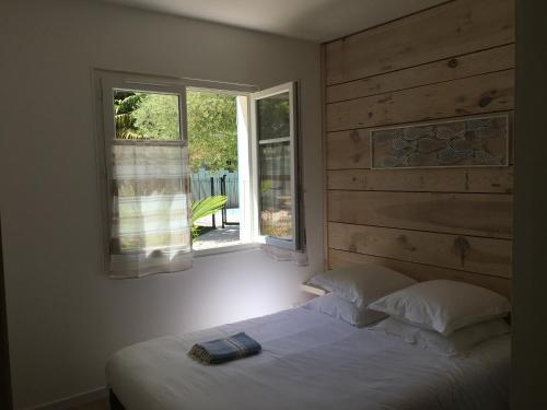 a bedroom with a bed and a window with a book on it at Les Suites de l'Alvertonne in Arvert