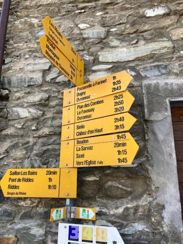 a bunch of yellow signs on a stone wall at Un moment de détente inoubliable Saillon-les-Bain in Saillon