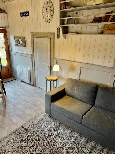 a living room with a couch and a clock on the wall at La Ferme de Marie in Rangen