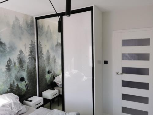 a bedroom with a forest mural on the wall at Apartament Ryś in Szklarska Poręba
