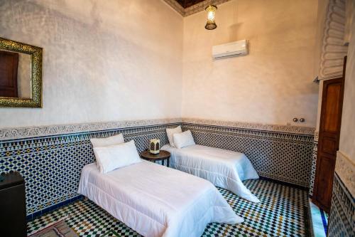 a room with two beds and a mirror at Riad Arabella in Fès