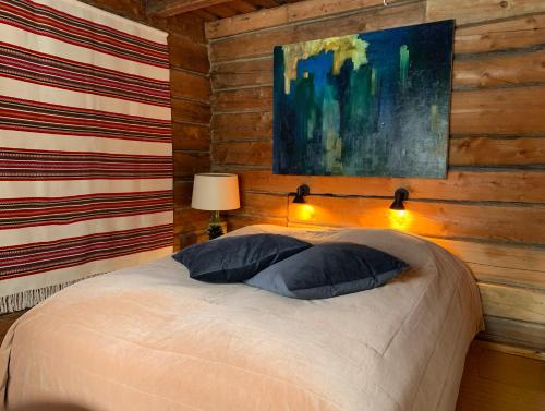 a bedroom with a bed and a painting on the wall at Saariselällä, sielukas hirsimökki - Unique cottage in Saariselka