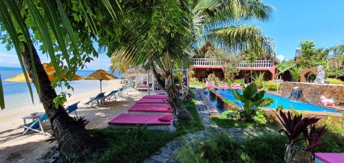 a resort with a pool and a beach with palm trees at Hotel ECOLODGE LE RAVORAHA in Sainte Marie