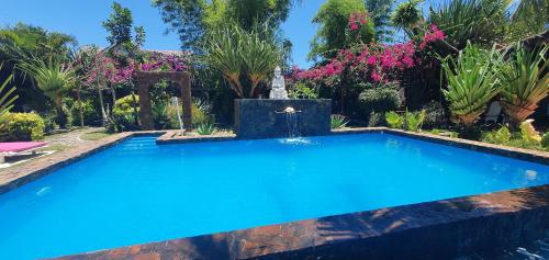 a swimming pool with a fountain in a garden at Hotel ECOLODGE LE RAVORAHA in Sainte Marie