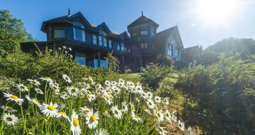 a large house on top of a hill with flowers at Las Balsas Relais & Chateaux in Villa La Angostura