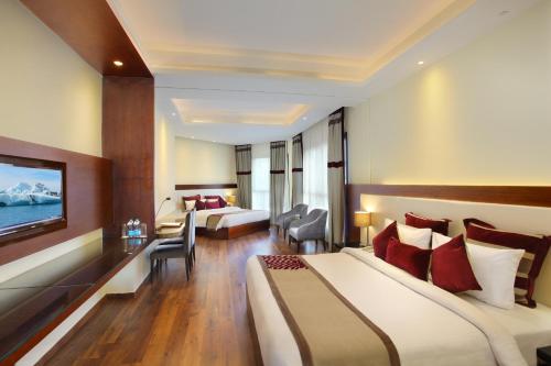 a hotel room with two beds and a television at Marigold Sarovar Portico Shimla in Shimla