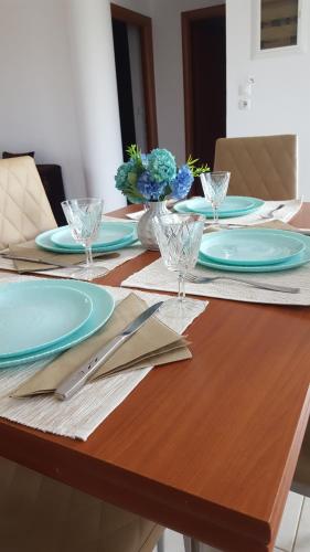 una mesa de madera con placas azules y vasos. en Theti Apartment, en Faliraki