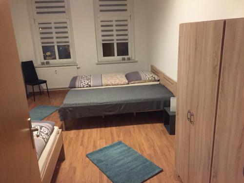 a small bedroom with a bed and two windows at Ferienwohnung am Holzwurm in Riesa