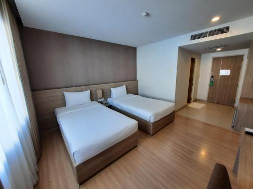 a small room with two beds and a window at Leosor Hotel in Nakhon Ratchasima