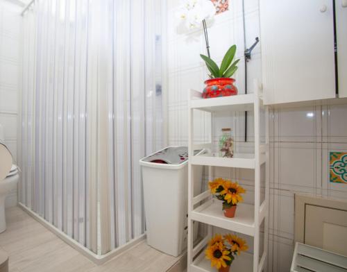 łazienka z białą półką z kwiatami w obiekcie Casa RosaMaria w mieście Giardini Naxos