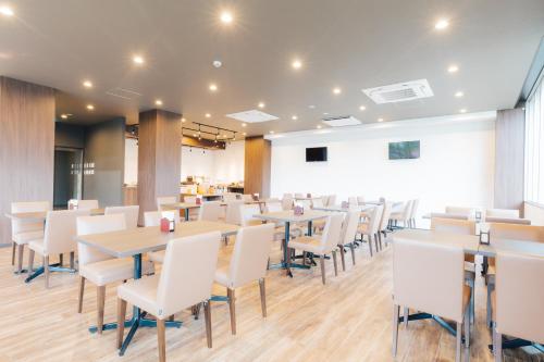 a dining room with tables and white chairs at Hotel KAN-RAKU Fujisan Gotemba in Gotemba