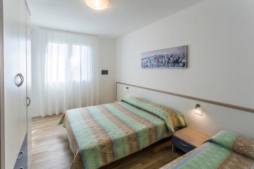 a small bedroom with a bed and a window at MIMOSE Lido Altanea in Caorle