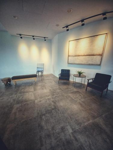 a room with two chairs and a bench and a painting at 埔里隱巷人文行旅民宿 in Puli